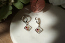 Pair of silver earrings with floral designs on a white surface.