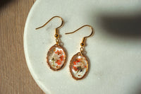 Gold earrings with floral designs on a white plate
