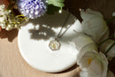 Necklace with a floral pendant on a white stone surrounded by flowers