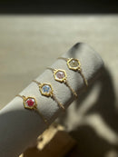 Gold bracelets with hexagonal gemstones on a white surface