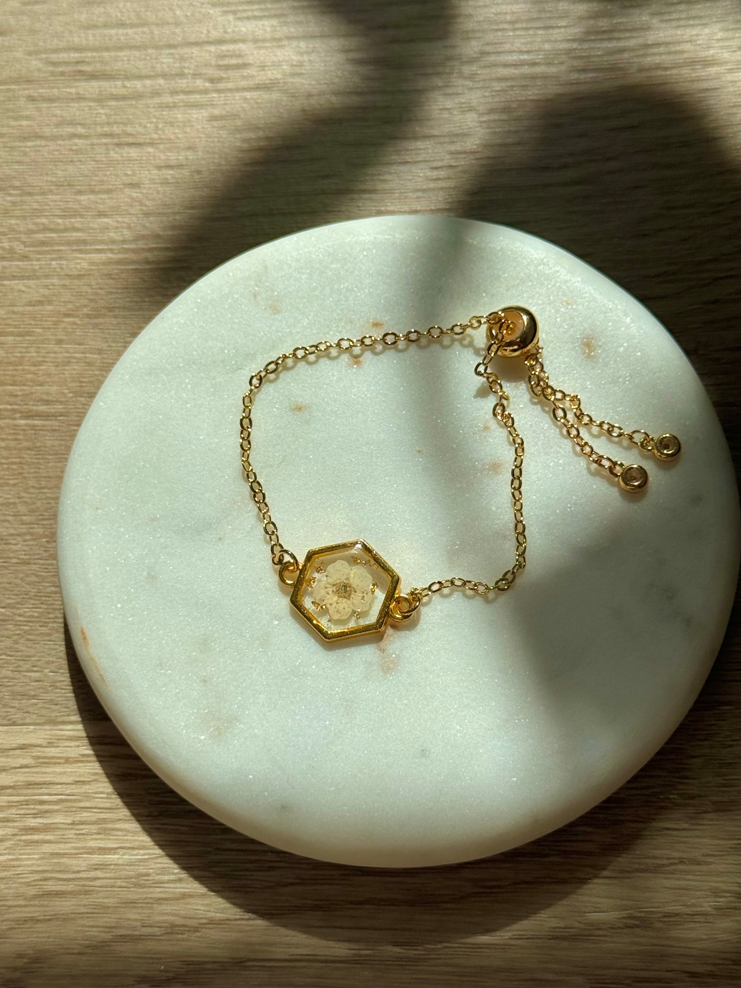 Gold bracelet with a hexagonal stone on a marble surface